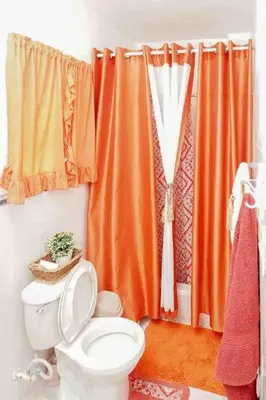 a bathroom with a toilet and an orange shower curtain at Apartamento en la Romana 2 días en adelante in La Romana