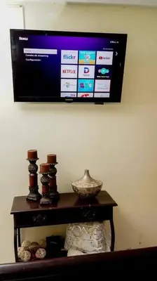 a television hanging on a wall above a table at Apartamento en la Romana 2 días en adelante in La Romana