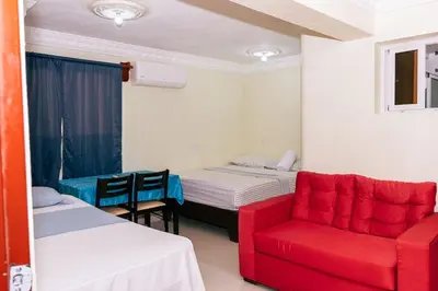 a room with two beds and a red chair at Comfort Double Room - Corales del Sur Ole Las Americas- Isabelita - Aeropuerto in La Viva