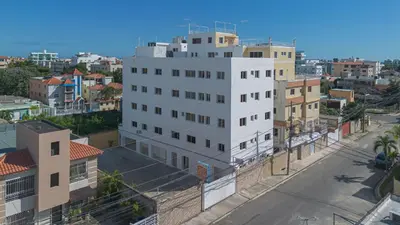 a tall white building in a city with buildings at Comfort Double Room - Corales del Sur Ole Las Americas- Isabelita - Aeropuerto in La Viva