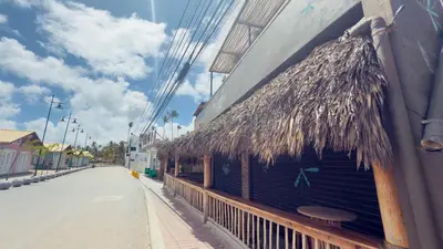 a building with a straw roof on the side of a street at Don Cesar Beachfront Apartments in Las Terrenas
