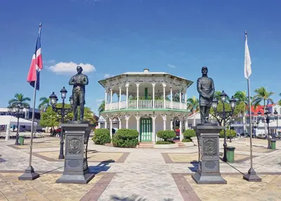two statues of men in front of a building with flags at Villa Bellevue in San Felipe de Puerto Plata