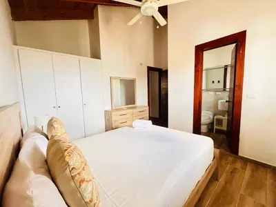 a bedroom with a large white bed and a bathroom at Paraíso Bayahibe in Bayahibe