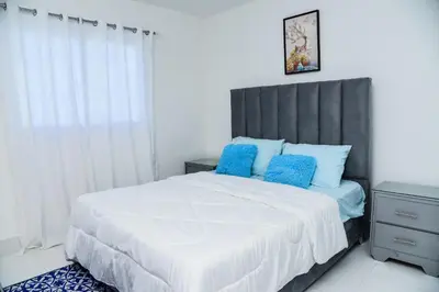 a bedroom with a large bed with blue pillows at Torre Real VI in Santiago de los Caballeros