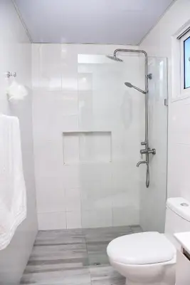 a white bathroom with a shower and a toilet at Torre Real VI in Santiago de los Caballeros