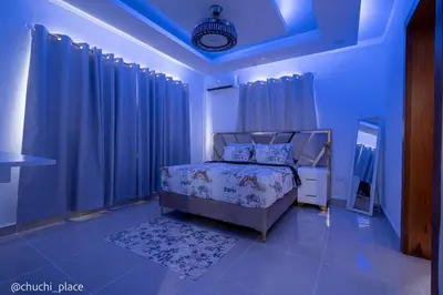 a bedroom with a bed with blue lights and curtains at Chuchi Place in Santiago de los Caballeros