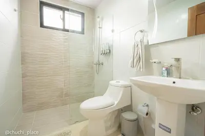 a white bathroom with a toilet and a sink at Chuchi Place in Santiago de los Caballeros