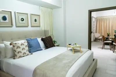 a bedroom with a large white bed with blue pillows at Brickell Apart Hotel in Santo Domingo
