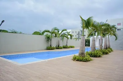 a swimming pool with palm trees next to a building at The apartment you dreamed of 1 in Santiago de los Caballeros