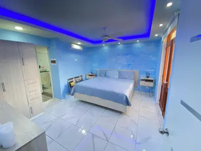 a blue bedroom with a bed and a bathroom at Hotel Checo Sosúa in Sosúa