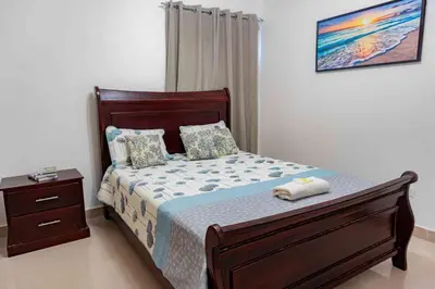 a bedroom with a bed with a wooden frame and a night stand at 2 Bedrooms at Baia Residences in Santiago de los Caballeros
