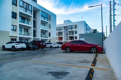 a red car parked in a parking lot next to buildings at 2 Bedrooms at Baia Residences in Santiago de los Caballeros