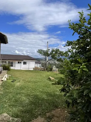 a yard with a white building and a field of grass at Villa Ladera de la Montańa in Jarabacoa