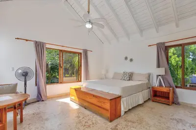 a bedroom with a bed and a desk and windows at Río Mar Cumayasa in La Romana