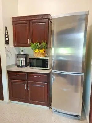a kitchen with a stainless steel refrigerator and a microwave at Bright & Modern Apartment in Puerto Plata, Secure, and Central! in San Felipe de Puerto Plata