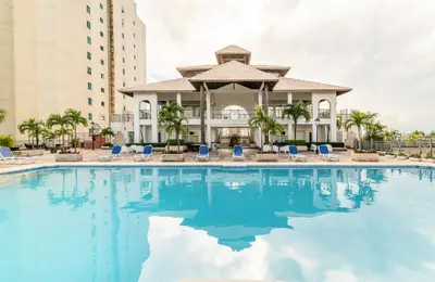a large swimming pool with blue chairs and a building at Gateway For You And Your Loves Ones I Sleeps 6 in Santo Domingo