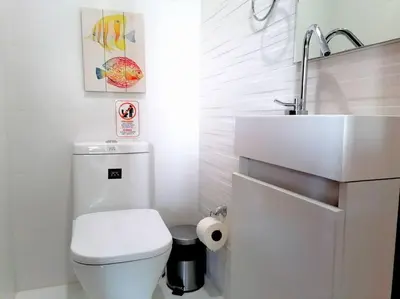 a white bathroom with a toilet and a sink at Suites Room Soha II in Santiago de los Caballeros