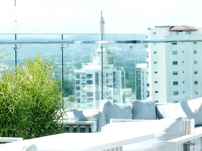 a balcony with white furniture and a view of a city at Suites Room Soha II in Santiago de los Caballeros