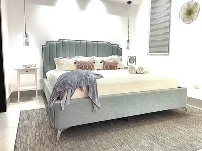 a bedroom with a large bed with a gray headboard at Paradise Room Rialto Residences in Santiago de los Caballeros