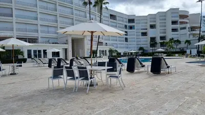 a table with chairs and an umbrella in front of a building at Your Little Paradise - Juan Dolio in Juan Dolio