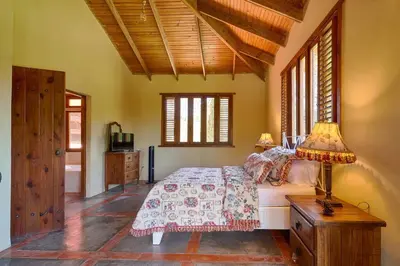 a bedroom with a bed and a table with a lamp at Escape Chalet at Pinar del Sol in Jarabacoa in Jarabacoa