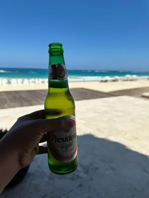 a person holding a bottle of beer at the beach at LUXURY CONDO Cana Bay 1 CLUB BEACH in Punta Cana