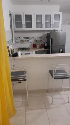 a kitchen with white cabinets and two chairs and a counter at RG Sol 1 in Pantoja