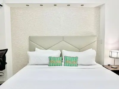 a bedroom with a white bed with two pillows at Confort y estilo en Galería 360 con piscina y gimnasio in Santo Domingo