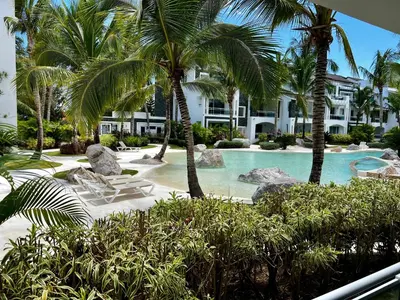 a resort with a swimming pool with palm trees at Apartment in Estrella, Dominicus-Bayahibe in La Laguna