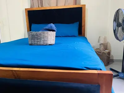 a bed with a blue blanket and a basket on it at Casa Bonita Pimentel in Pimentel