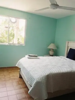 a bedroom with a white bed and a blue wall at LA CASA DE MAMA LUZ in San Felipe de Puerto Plata