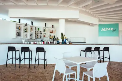 a bar with white chairs and a white table at Hotel HM Alma de Bayahibe - Adults Only - All Inclusive in Bayahibe