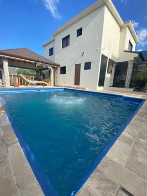 a blue swimming pool in front of a house at VillaLunaCaridad in Jarabacoa