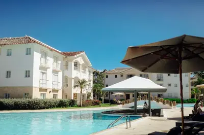 a swimming pool with an umbrella and some buildings at Apartment in Dominicus in Bayahibe
