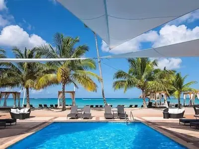 a swimming pool next to a beach with palm trees at Apartment in Dominicus in Bayahibe